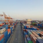 Cargo containers at a busy port at sunrise